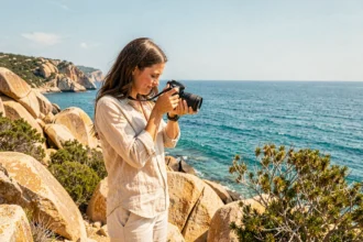 Photographe professionnelle ajustant son appareil photo sur les falaises rocheuses près de Porto-Vecchio en Corse